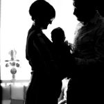 Heartwarming silhouette of parents holding their baby in a black and white setting.